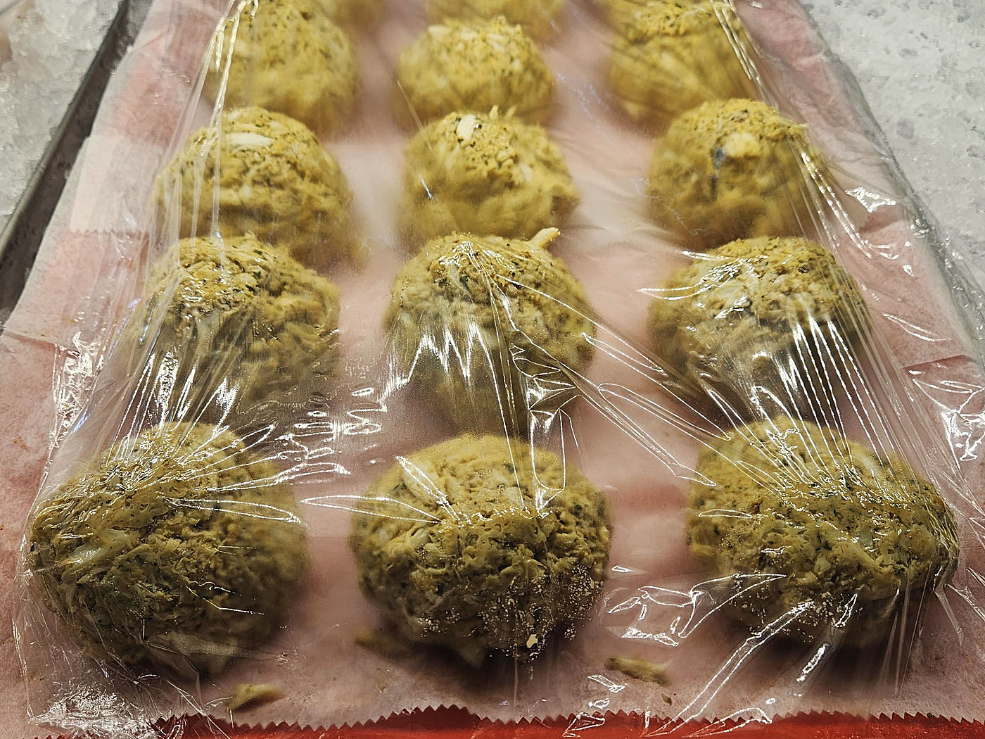 Rows of crab cakes on a tray set in ice